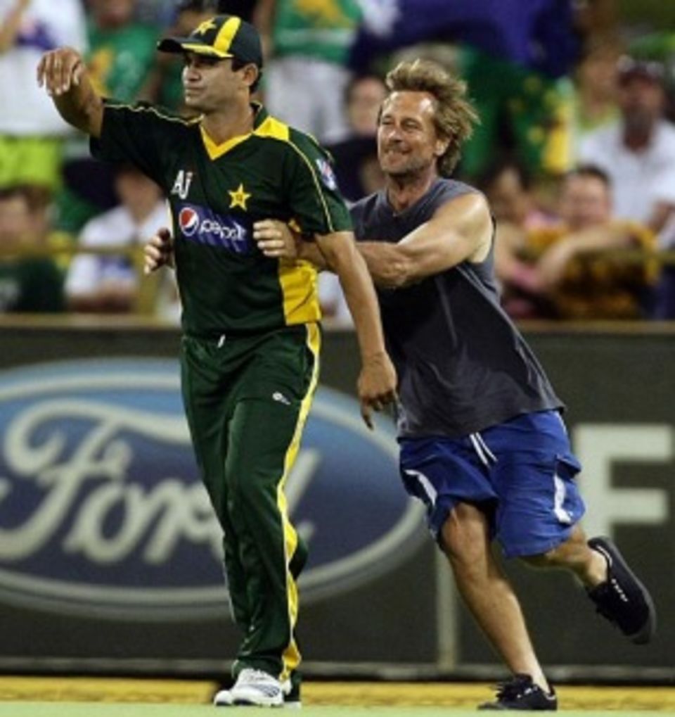 Khalid Latif is about to be brought down by a pitch invader