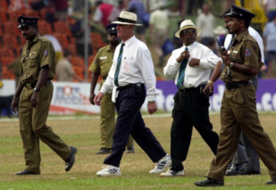 Rudi Koertzen and Cooray are escorted off the field by security officials on the fourth day