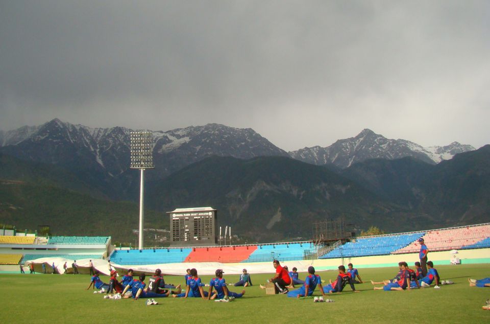 The players ring their coach at the HPCA Stadium in Dharamsala, with the Himalayas looking on