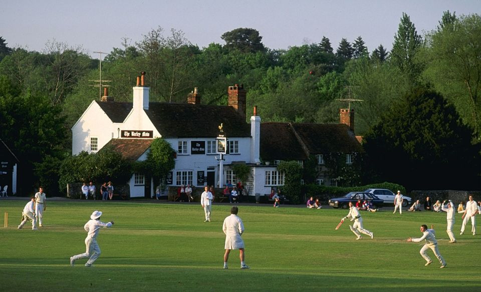 Summertime: village cricket at Tilford in Surrey with the Barley Mow pub in the background