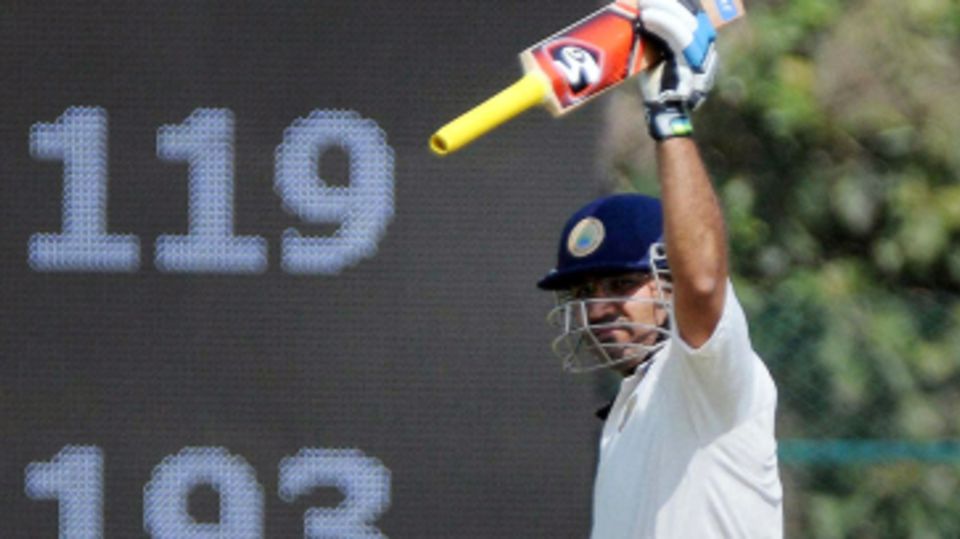 Virender Sehwag raises his bat after scoring a century against Karnataka