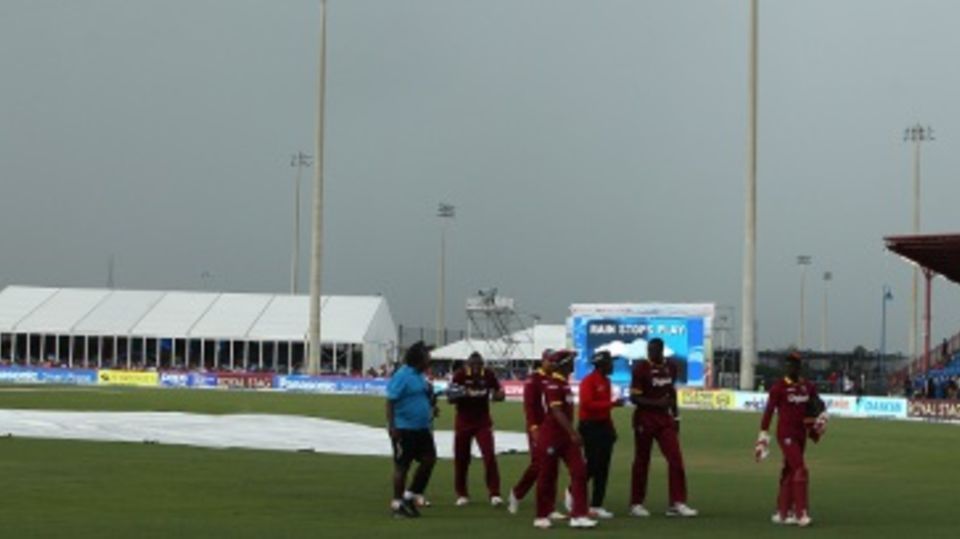 West Indies players walk off the field as dark clouds envelop the sky and the rain comes down