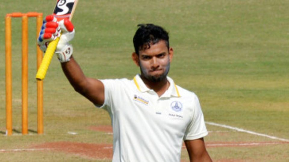 Kaushik Gandhi raises his bat after reaching his 150