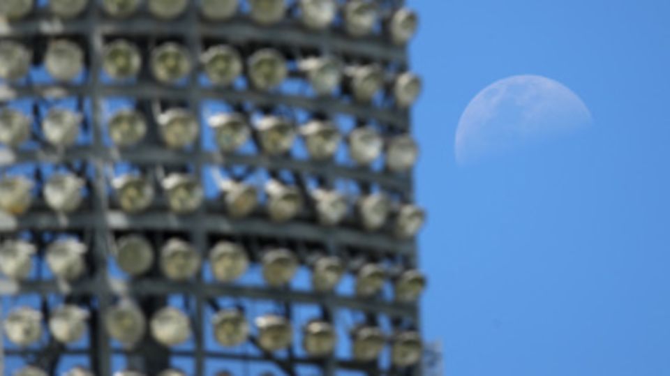 The moon was visible behind one of the light towers