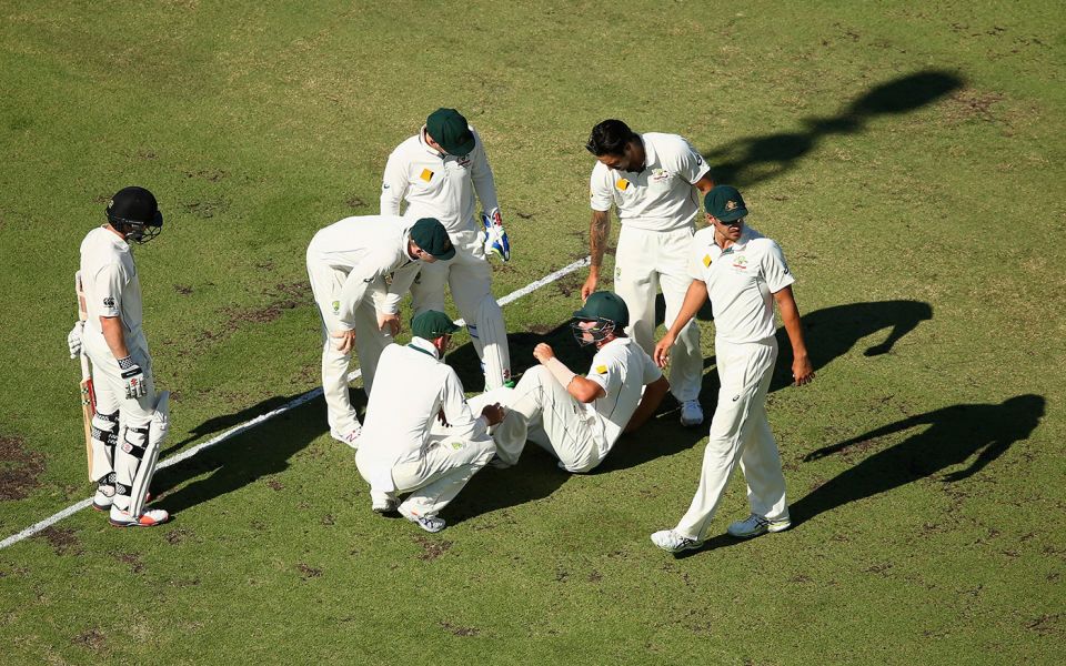 Australian fielders crowd around Joe Burns after he was struck on the helmet while fielding close to the bat in Perth in 2015