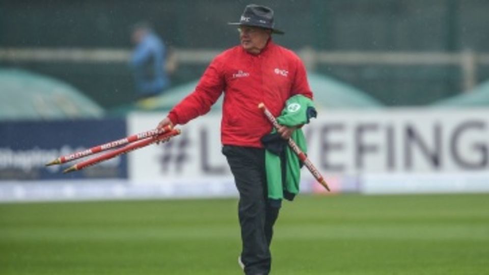 Umpire Ian Gould walks off with the stumps after rain interrupts play