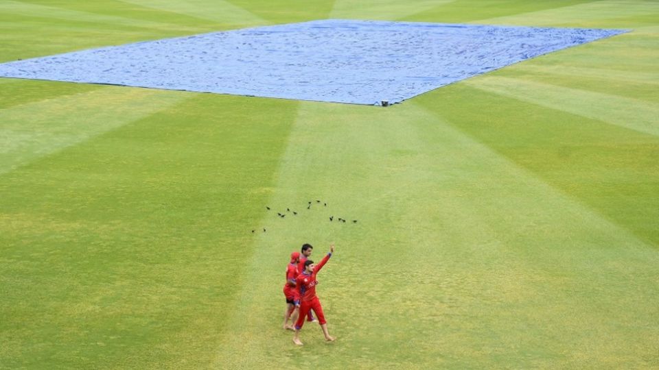 Rashid Khan, Javed Ahmadi and Nasir Jamal walk around the wet outfield