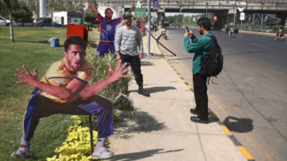 Fans pose next to cut-outs of Hasan Ali and Shahid Afridi ahead of the final