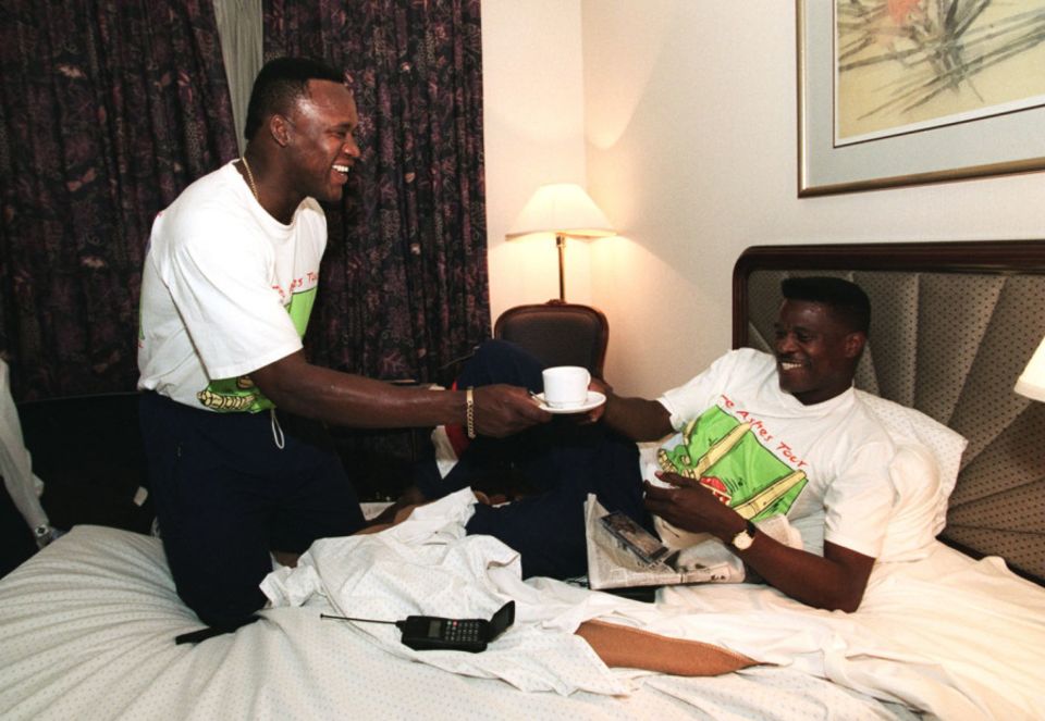 Devon Malcolm offers a cup of tea to his chicken-pox-afflicted team-mate Joey Benjamin in his hotel room