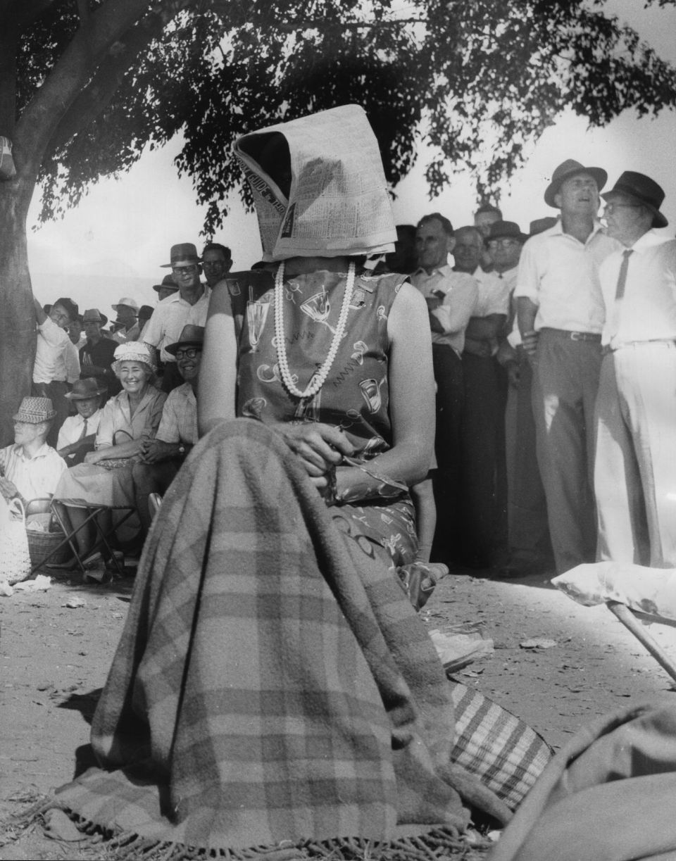 A newspaper does double duty for a fan on a hot afternoon at The Gabba in 1962
