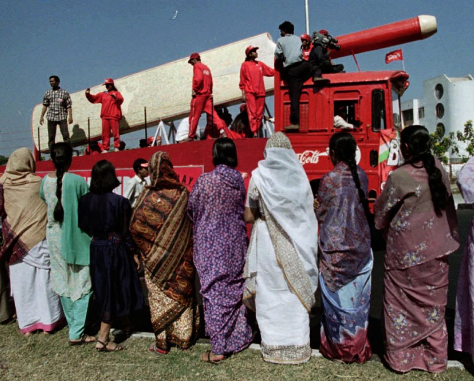 Women in Calcutta watch a giant bat being driven past in a parade for the World Cup
