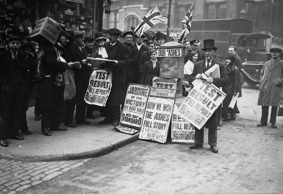 A newspaper seller on Farringdon Street, London uses his stand to celebrate England's 1932-33 Ashes victory