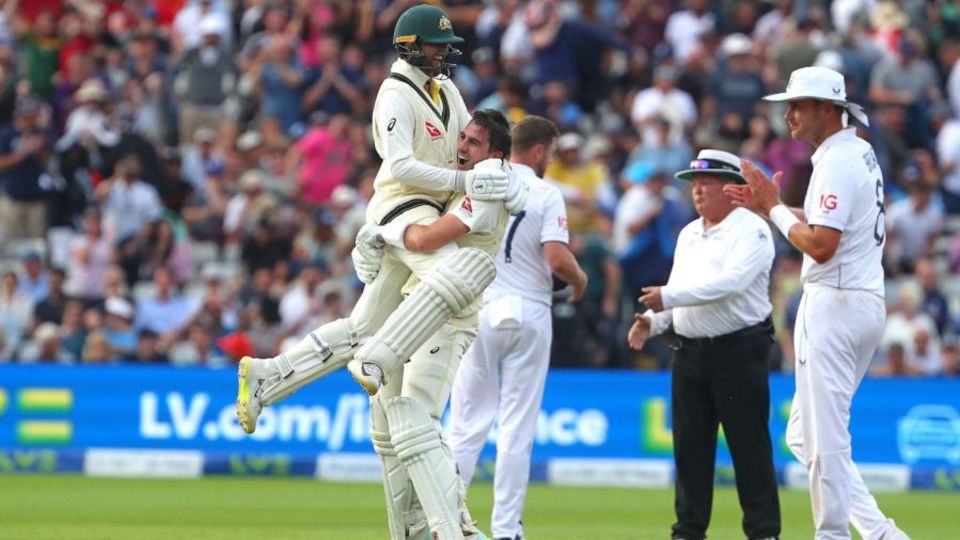 Nathan Lyon climbs on Pat Cummins as Stuart Broad applauds Australia's win