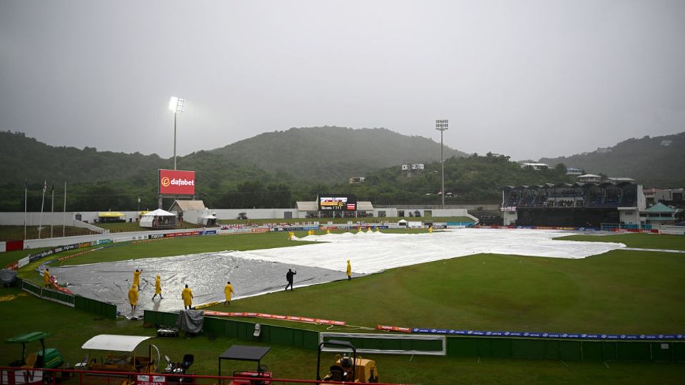 Ground staff bring on the covers as rain stops play