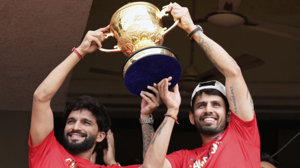 Rajat Patidar and Jitesh Sharma hold the IPL trophy up for the fans