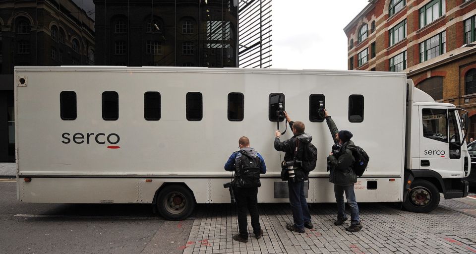 Photographers take pictures through the window of a prison van as it leaves Southwark Crown Court