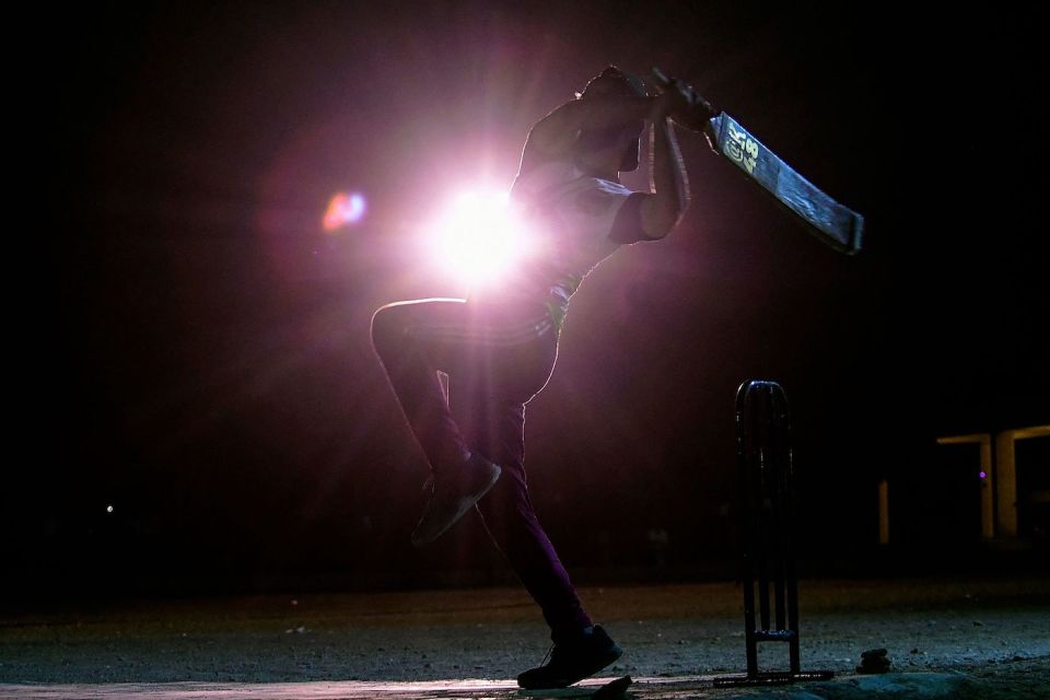 Shine on: a tape-ball player on the streets of Karachi strikes a dramatic pose