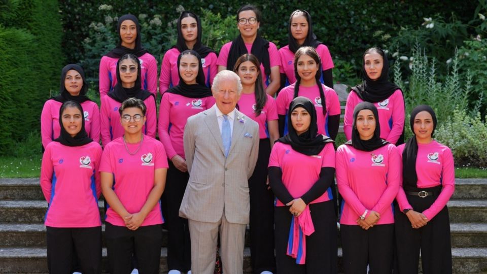 Members of the Afghan Refugee Women's team pose with Britain's King Charles III on the sidelines of the T20 World Cup