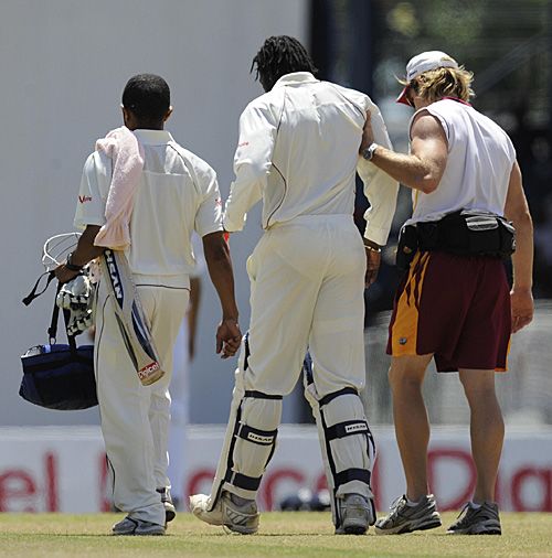 Chris Gayle is helped from the field by the West Indies physio, CJ Clark