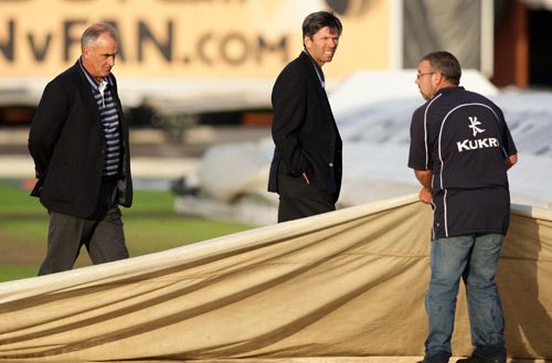 Umpires Peter Hartley and Nigel Llong conduct a doomed pitch inspection at Old Trafford