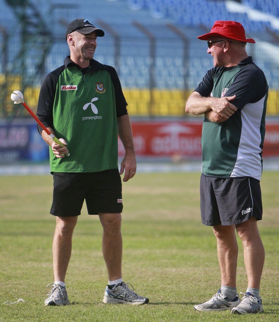 Alan Butcher and Jamie Siddons stand on a wet outfield at the Zohur Ahmed Chowdhury Stadium