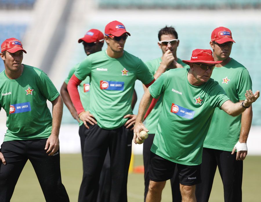 Zimbabwe players watch as coach Alan Butcher demonstrates a point
