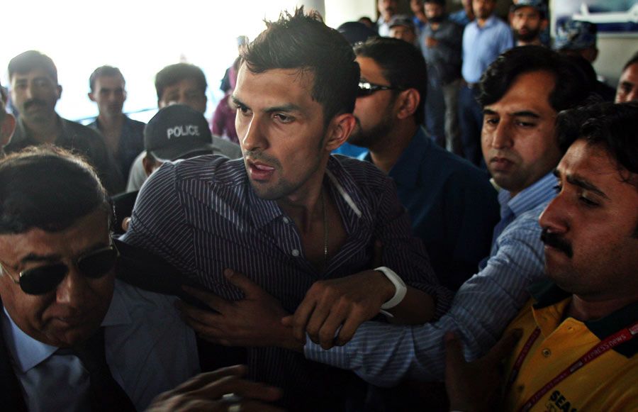 Zulqarnain Haider is escorted by security guards at Islamabad airport
