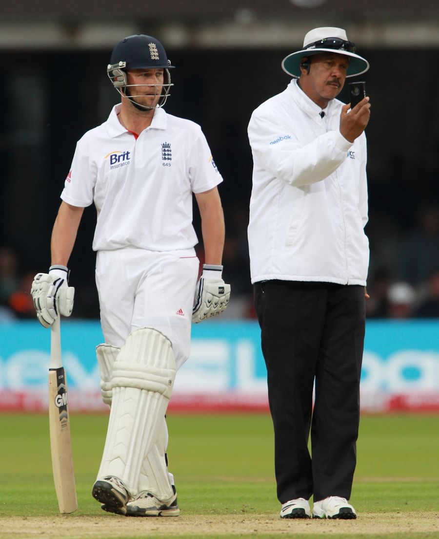 Umpire Billy Doctrove consults his lightmeter as Jonathan Trott looks on