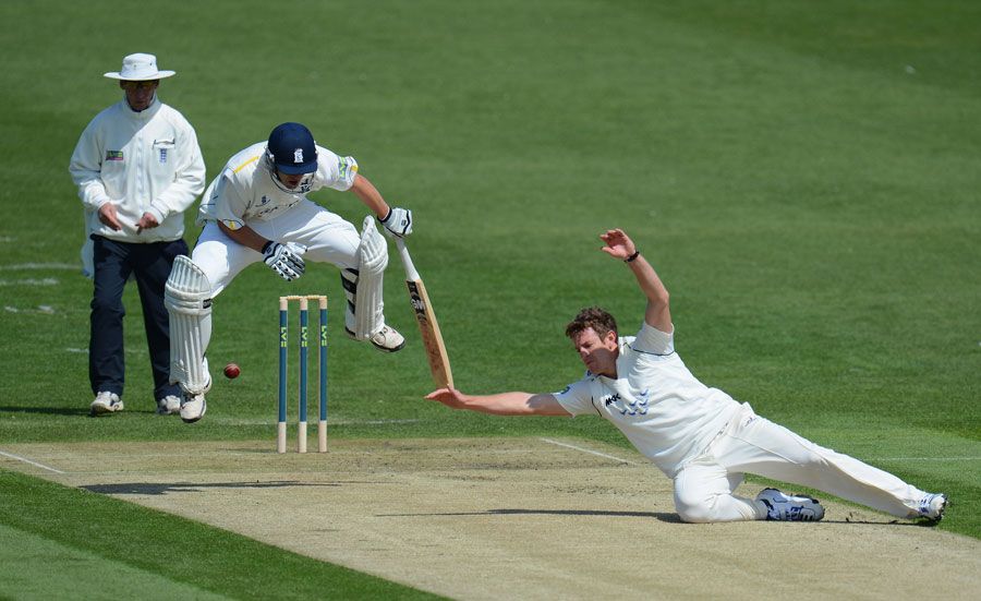 Jonathan Trott jumps in the air as James Anyon dives after the ball