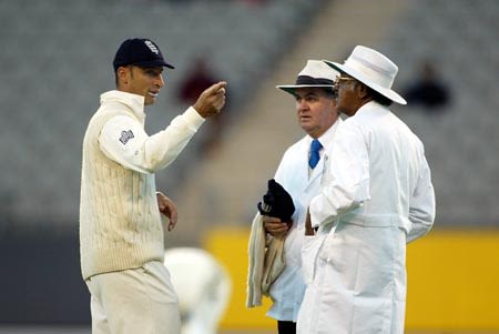 Nasser Hussain discusses the light conditions with umpires Cowie and Venkataraghavan