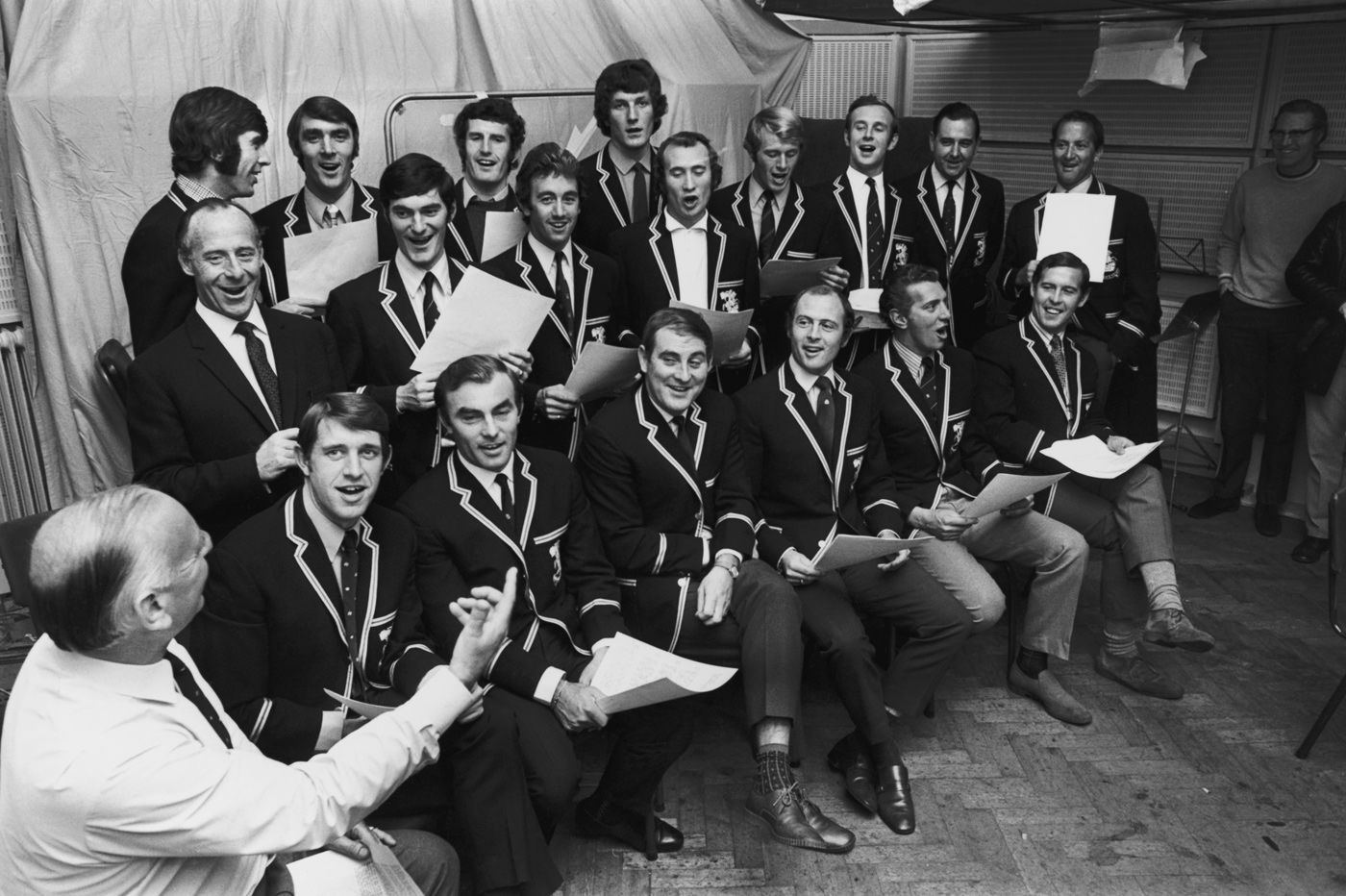 Commentator Brian Johnston conducts the victorious England squad in a rendition of "The Ashes Song" at the Decca studio in London