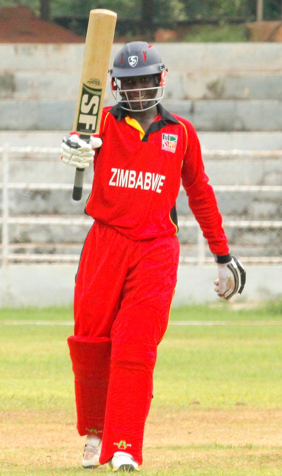 Clive Chitumba raises his bat after hitting fifty