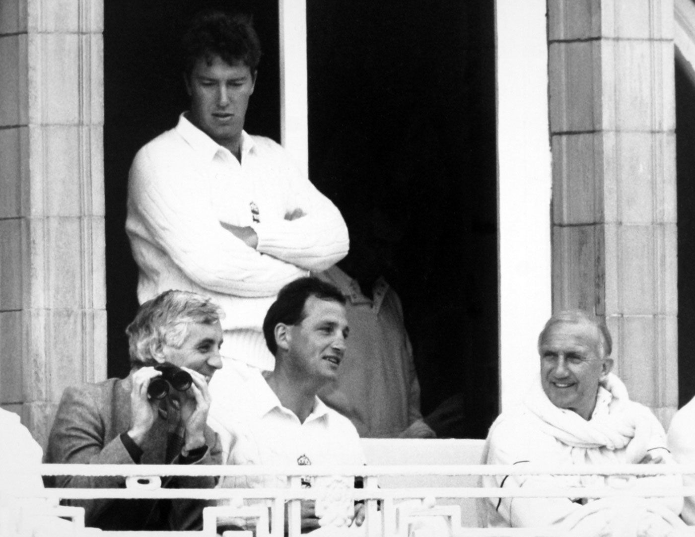 Former England captain Mike Brearely sits with current captain John Emburey and manager Micky Stewart in the balcony, and bowler Derek Pringle stands at the back