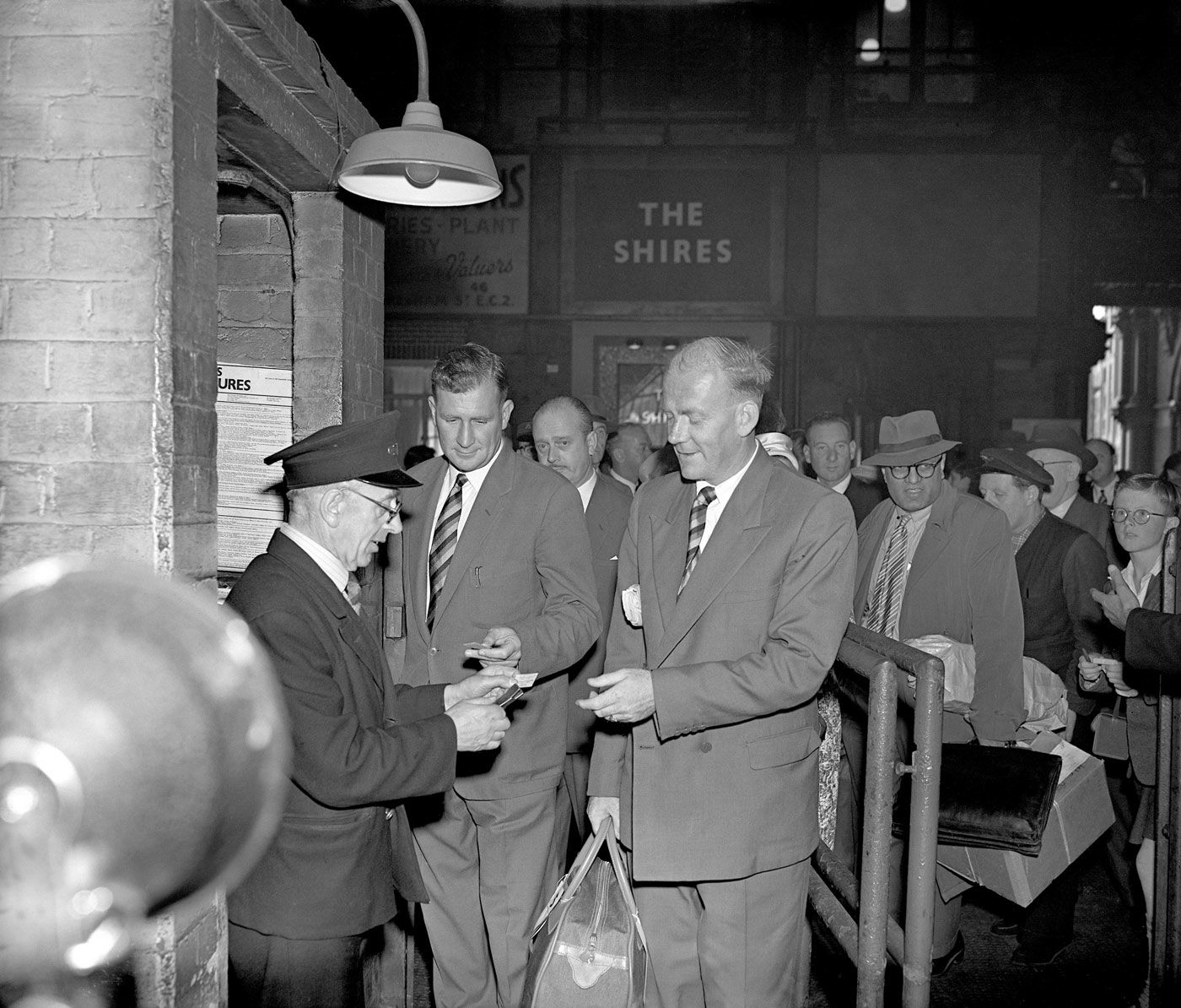 Jim Laker and Tony Lock have their tickets inspected before they board a train at St Pancras station on their way to Australia