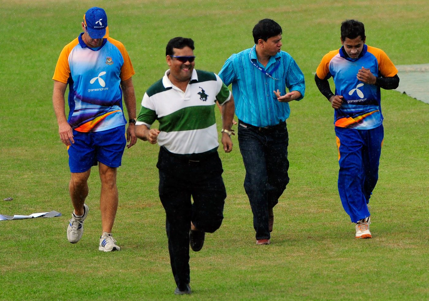 Mushfiqur Rahim, Minhajul Abedin and Akram Khan run to take shelter from the rain