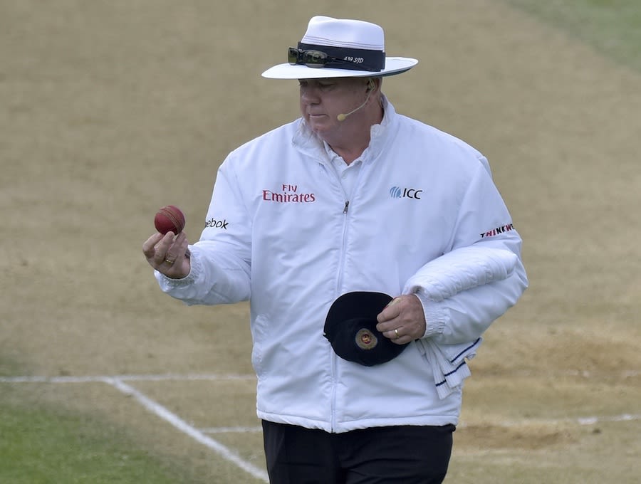 Umpire Steve Davis looks at the ball before changing it