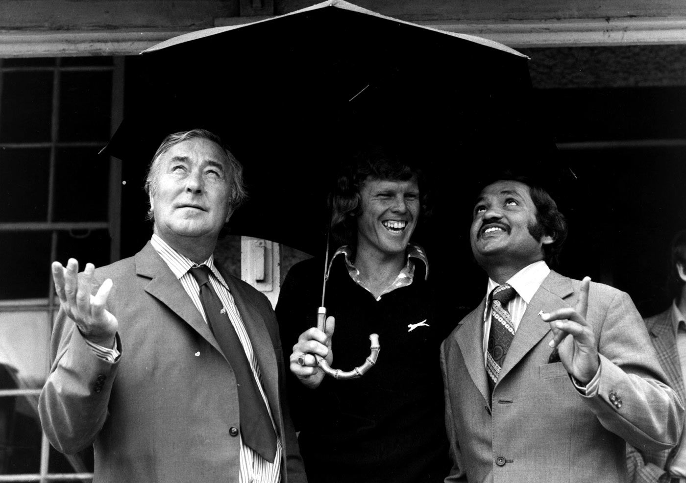 Denis Compton, Barry Richards and Mushtaq Mohammad shelter from the rain during a charity match in London