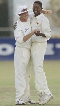 Brighton Watambwa and Guy Whittall celebrate the wicket of Javagal Srinath