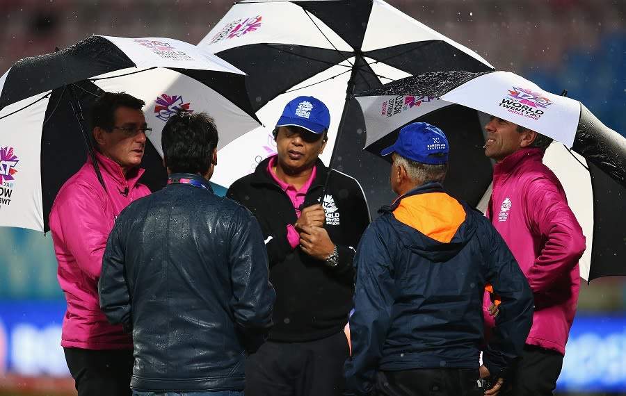 Match umpires have a chat with the groundstaff as rain stops play