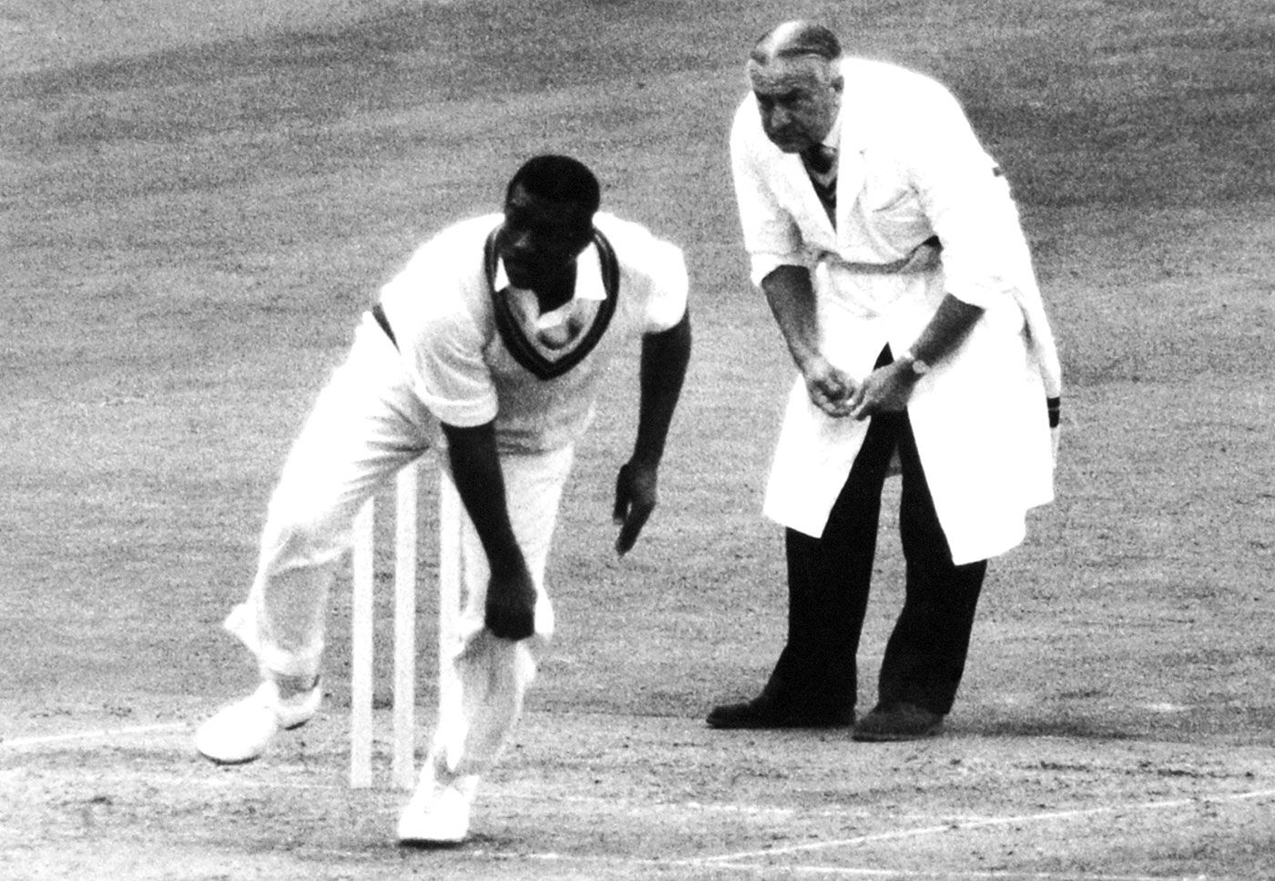 Charlie Griffith bowls as umpire Syd Buller looks on