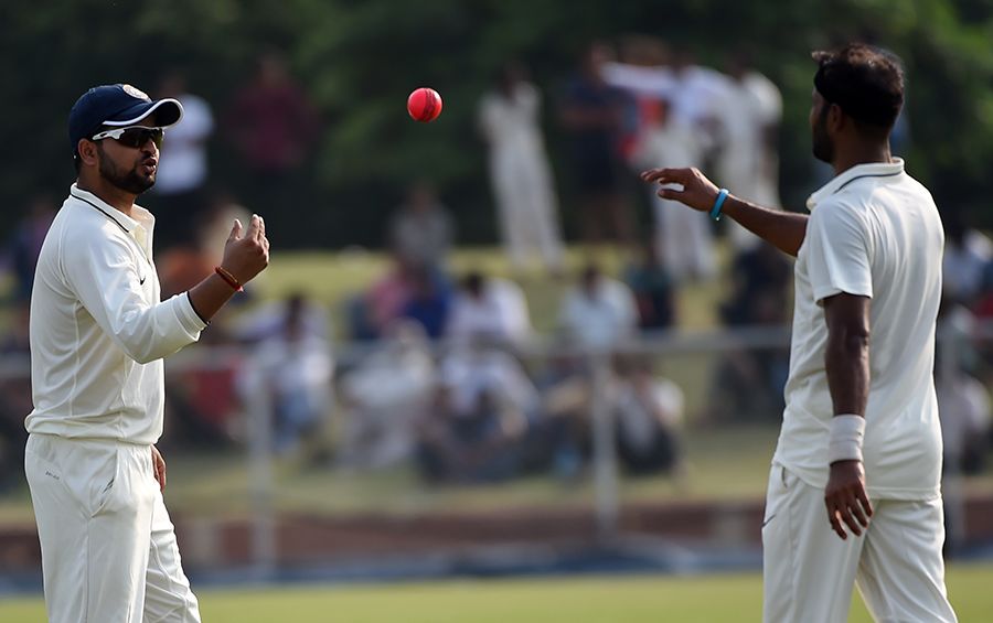 Suresh Raina tosses the pink ball to bowler Ashok Dinda