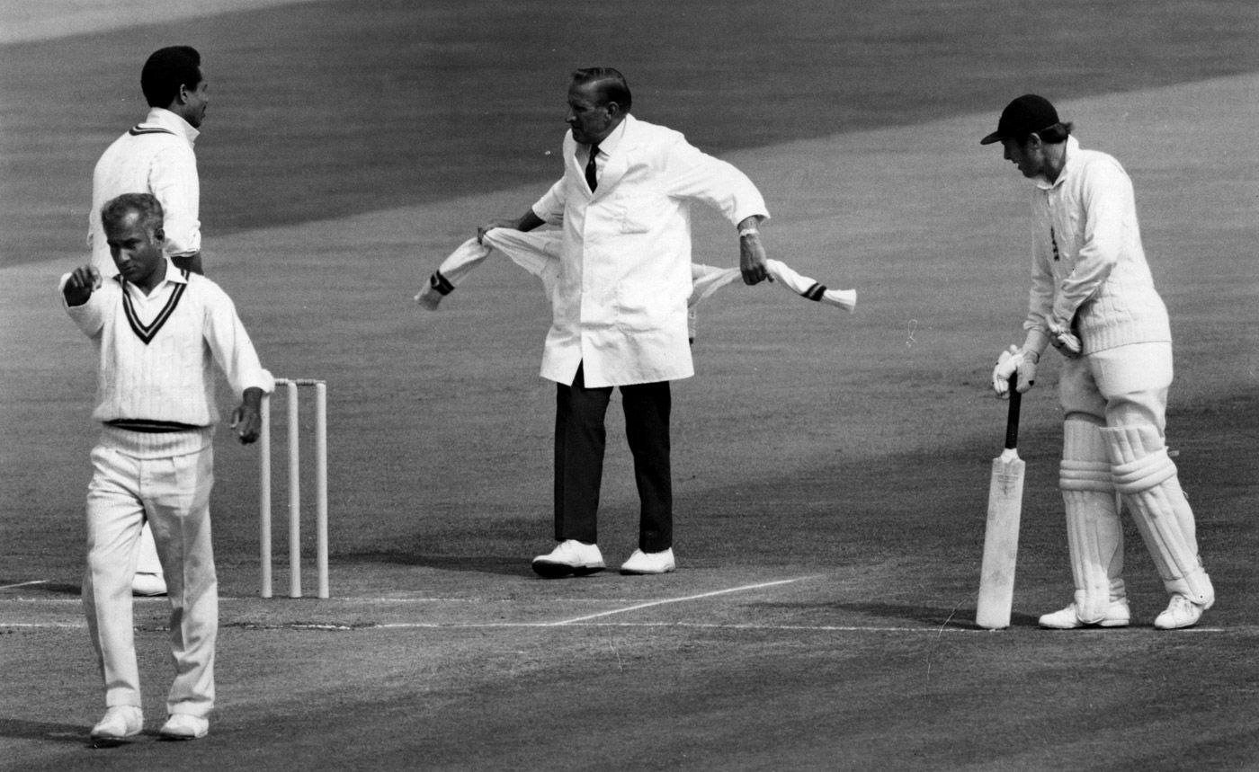 Umpire Arthur Fagg ties a sweater around his waist