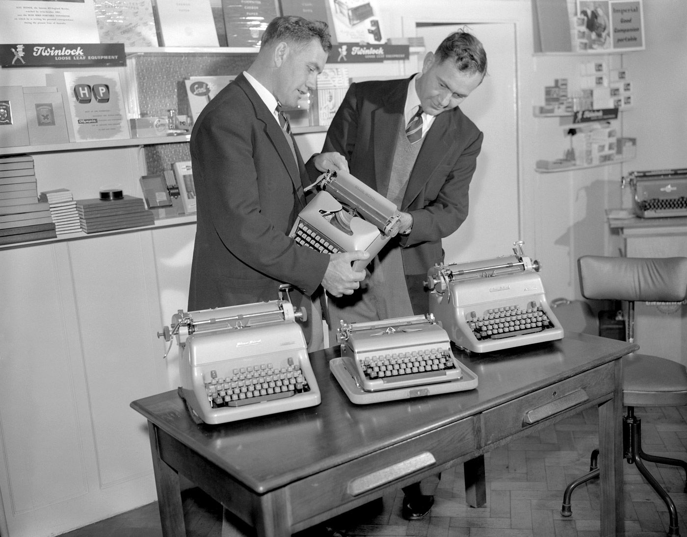 Alec (left) and Eric Bedser look at typewriters in their office equipment store in Woking