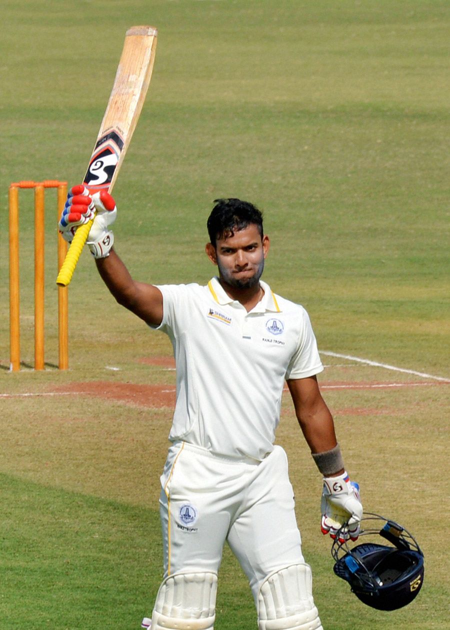 Kaushik Gandhi raises his bat after reaching his 150