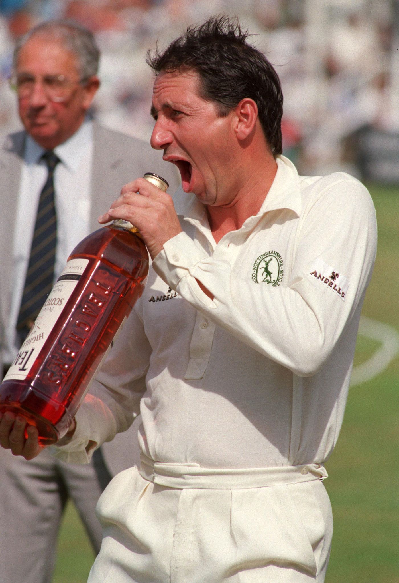 Derek Randall fools around with a bottle of whisky