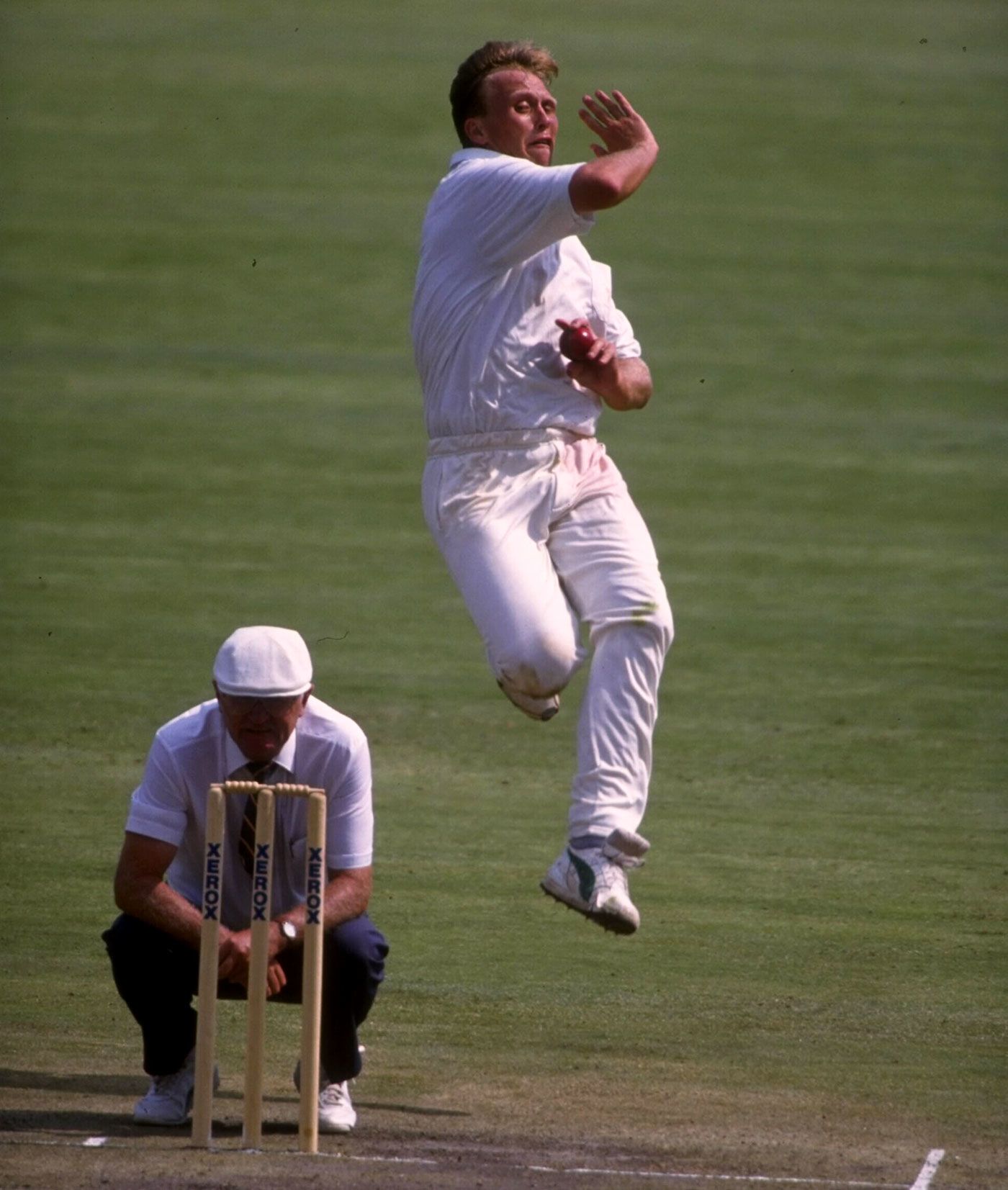 Fast bowler Brett Schultz bowls, watched by umpire Cyril Mitchley