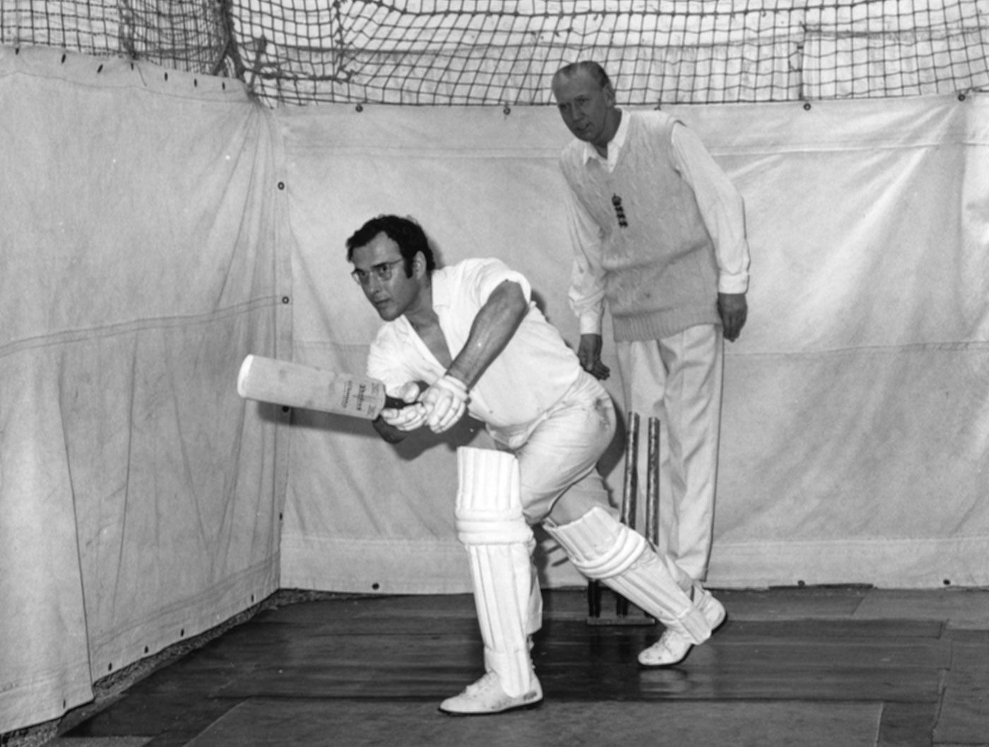 Playwright Harold Pinter bats in the nets watched by coach Alf Gover in his indoor cricket school in London