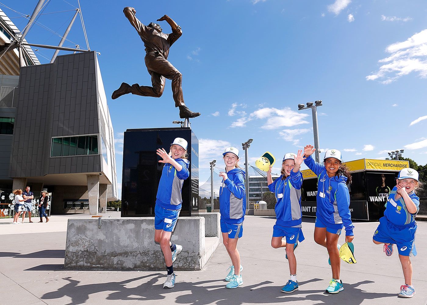 Young fans imitate Dennis Lillee's bowling action under his statue at the MCG
