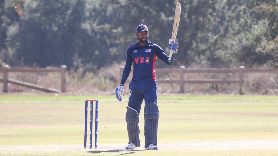 Alex Amsterdam raises his bat after reaching a half-century