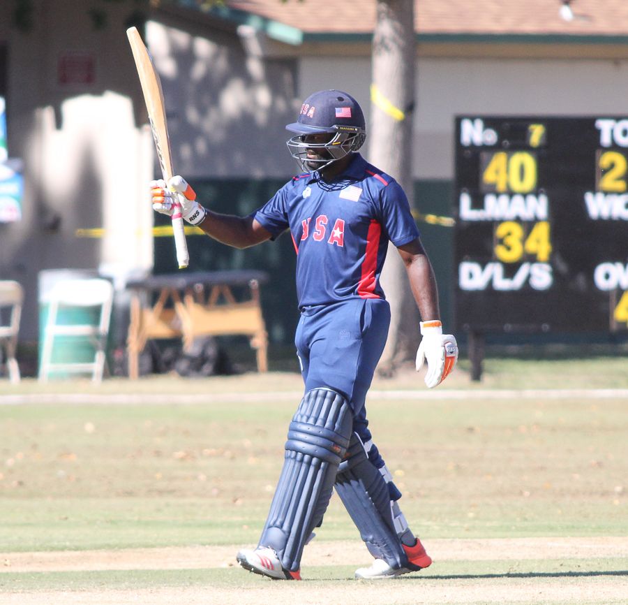 Nicholas Standford raises his bat after reaching a half-century